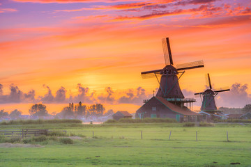 traditional village with dutch windmills and river at sunset, holland, netherlands.
