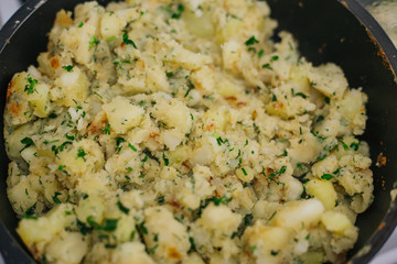 Potatoes with greens in a pan. Stewed potatoes with dill.