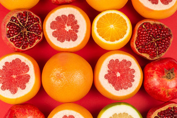 Grapefruit, orange, pomegranate, citrus sweetie on red background.