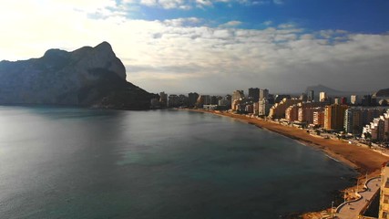 Wall Mural - Aerial view of Calpe city in Alicante, Spain, at sunrise. La Fossa beach is in the foreground and de Ifach Penon rock in the background.