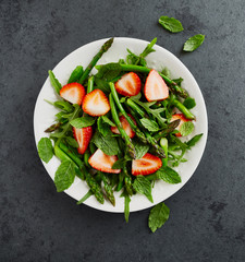 Wall Mural - Green asparagus, arugula and strawberry salad with mint leaves. From above