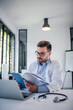 © bnenin - Portrait of a doctor in medical office reading textbook.