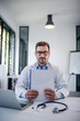 © bnenin - Portrait of a doctor in medical office, holding blank paper.