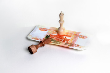 a black chess piece fell in front of a white chess piece on a wad of Russian money. on light background