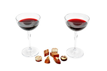 Two glasses with wine and chocolates isolated on a white background.