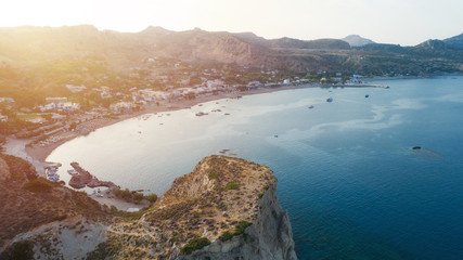 A landscape of sea in Greece surrounded by rocky mountains and greenery under a sunset sky. Rhodes island.