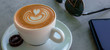 Apetitoso café servido en una taza blanca, con y una bella imagen dibujada en la superficie