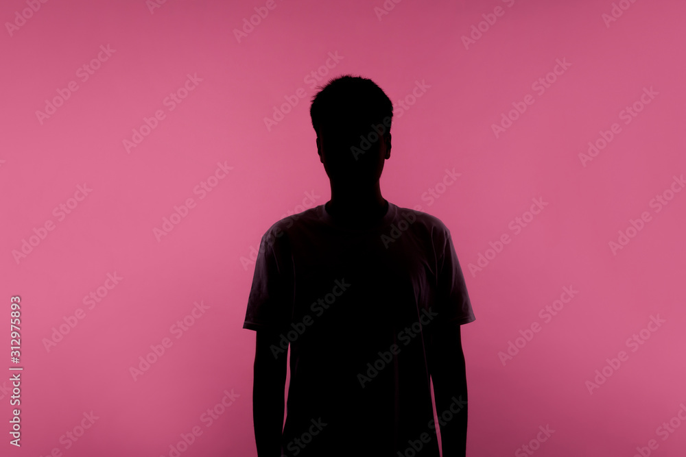 No name, anonymous person hiding face in shadow, human identity. Silhouette portrait of young man in casual T-shirt standing calm with hands down, indoor studio shot, isolated on pink background - obrazy, fototapety, plakaty 