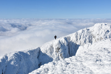 Lonely mountaineer get rest on snowy mountain high above the clouds. Happy climber enjoy in view from top of Dry Mountain, Serbia