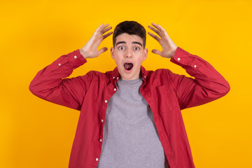 Wall Mural - young man or teenage student with astonishment or surprise expression isolated on yellow background