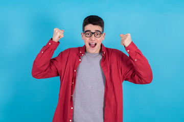 Poster - young man or teenage student isolated on color background with arms raised celebrating success