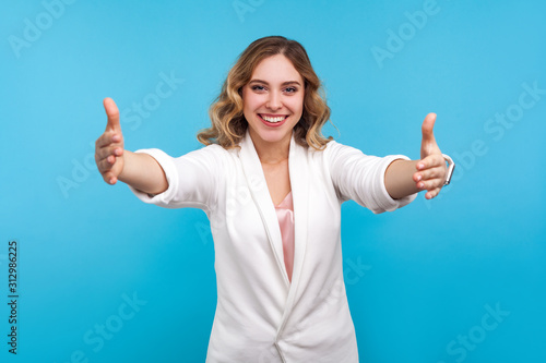 Photographie Free hugs! Portrait of hospitable good-natured woman with wavy hair in white jacket wants to embrace, welcoming with stretched hands, congratulating and rejoicing at your success