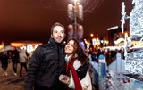 Fototapeta Miasto - Loving couple walks around the evening Christmas city in winter.
