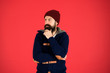 © be free - Fashion menswear shop. Masculine clothes concept. Think and decide. Winter menswear. Man bearded warm jumper and hat red background. Winter season menswear. Personal stylist. Warm and comfortable