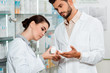 © LIGHTFIELD STUDIOS - Pharmacists in white coats looking at jar with pills in pharmacy