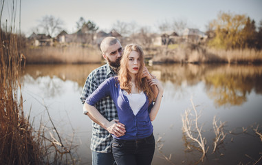 young and stylish couple standing near water in park