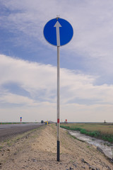 road sign on a background of blue sky c clouds next to the road. focus on the sign