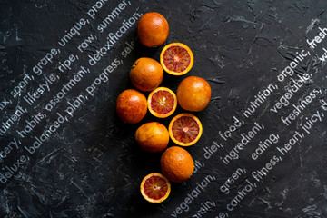 Wall Mural - flat lay of red sliced exotic oranges, dark food on black surfaces