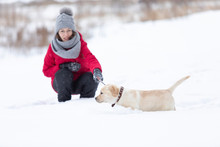 Young Beautiful Woman Walking In Snow With Her Dog On Snowy Winter Day
