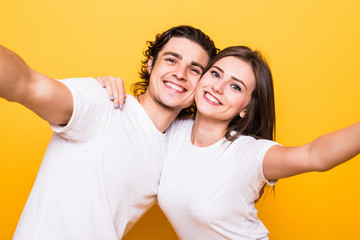 Sticker - Portrait closeup of joyful man and woman laughing and taking selfie photo isolated over yellow background