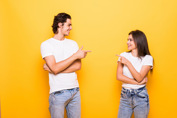 Sticker - Young people man and woman in basic clothing laughing and pointing fingers at each other isolated over yellow background