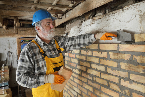 Cuadros en Lienzo Worker building brick wall in old barn