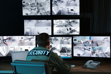 Security guard monitoring modern CCTV cameras in office