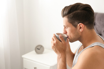 Canvas Print - Man with cup of coffee in bedroom. Lazy morning