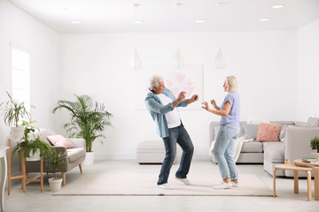 Wall Mural - Happy mature couple dancing together in living room