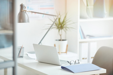 close-up of workplace with laptop and folder on it at light modern office