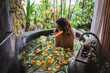 Young woman enjoying in outdoor luxury spa. Beautiful luxury stone bath tub with jungle view.Natural organic tropical ingredients in the water:ginger,lime,orange and sea salt. Beauty treatment concept