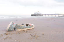 A Pair Of Shoes Abandoned On The Beach In Eastbourne With The Pier In The Background