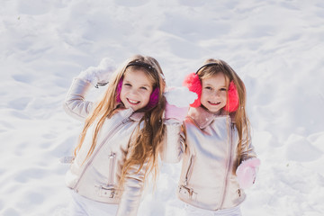 Winter children portrait. Portrait of two little girls play with snow in winter. Winter children posing and having fun.