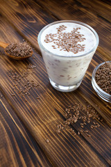 Wall Mural - Yogurt or kefir with flax seeds in the glass on the brown wooden  background. Location vertical. Copy space.