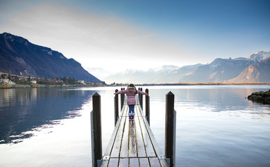 Asian  girl standing on the old wooden bridge happily in the natural scenery on the river in the lake next to the mountain