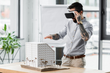 Wall Mural - virtual reality architect in virtual reality headset looking at model of house