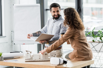 Wall Mural - virtual reality architects talking and pointing with finger at model of house