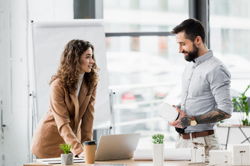 Wall Mural - smiling virtual reality architects standing near model of house and talking in office