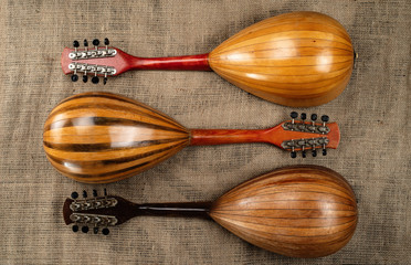 Wall Mural - Three old mandolins on a background of rough burlap texture. Back view.