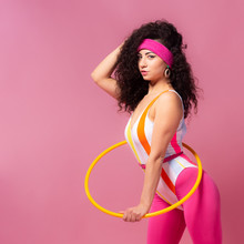Photo Of Slim Woman 80s Wearing Aerobic Clothes Doing Exercises With Hula Hoop During Gymnastics Against Pink Wall