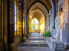 View Into The Sun Illuminated Corridors Of Campo Santo, A Grave Building On The West Cemetery In Aachen, Germany, Created Before 1900, A Sculpture Mourning Woman On The Right.