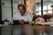 Senior Businessman Using Tablet And Girl Playing With Chameleon Figurine In Office