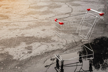 an empty grocery basket from the supermarket and its reflection in the rain in the Parking lot