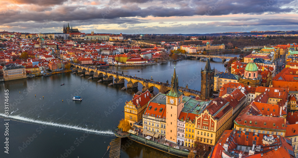 Prague, Czech Republic - Aerial panoramic drone view of the world famous Charles Bridge (Karluv most) and St. Francis Of Assisi Church with a beautiful winter sunset. St. Vitus Cathedral at background - obrazy, fototapety, plakaty 