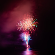 Multicolored Fireworks Exploding In The Air And Over The Sea Water At The Same Time. Happy New Year!!