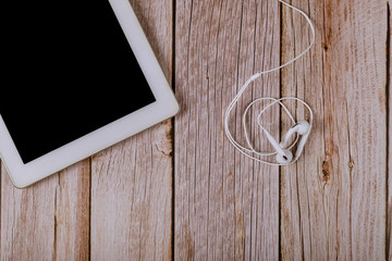 Digital tablet and headphones on wooden table