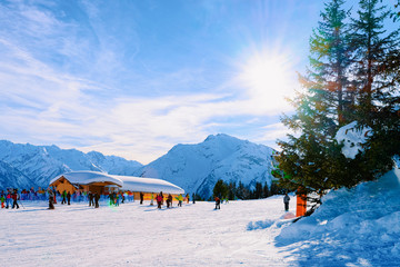 Canvas Print - People skiing and snowboarding on Penken ski resort in Tyrol in Mayrhofen in Zillertal valley in Austria in winter Alps. At Alpine mountains with white snow and blue sky. Sun flare at sunset