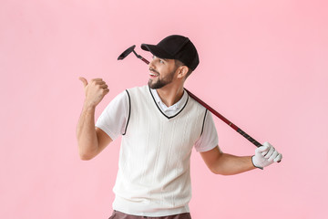 Wall Mural - Handsome male golfer pointing at something on color background