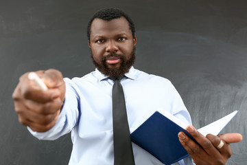 Wall Mural - Angry African-American teacher near blackboard in classroom