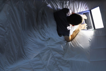 Man in bed with laptop using internet in online service